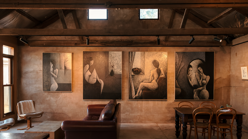 A shot of a seating area inside Wonderground Barossa. Comfy seats and table and chairs sit in front of a wall that's decorated with fine art.